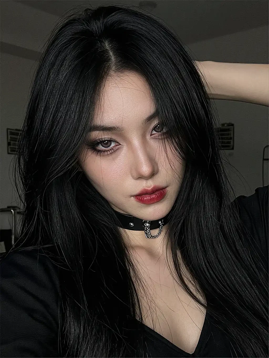 AI companion with long black hair, red lipstick and a chain choker in a black V-neck top